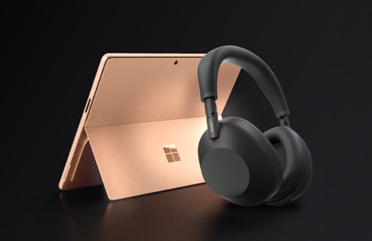 A 13-inch, Dune Surface Pro with a pair of black Sony wireless headphones.
