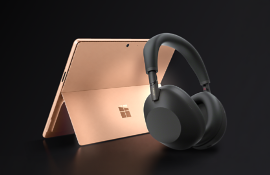 A 13-inch, Dune Surface Pro with a pair of black Sony wireless headphones.