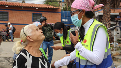 Members of disaster response team interacting with two elderly women while a man stands in the background.