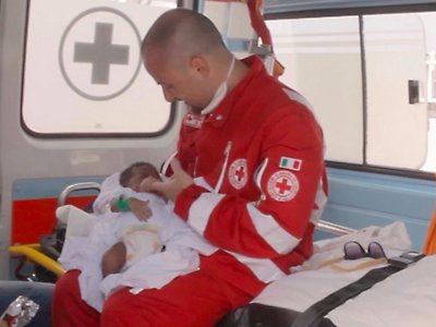 A Costa Rican Red Cross worker cradles an infant inside an ambulance, symbolizing compassion and humanitarian aid.