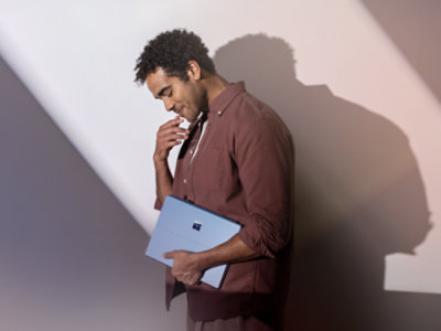 A young man holding a Sapphire Surface Pro 13. 