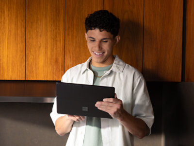 キッチンに立ち、黒いSurface Proを使っている男性。