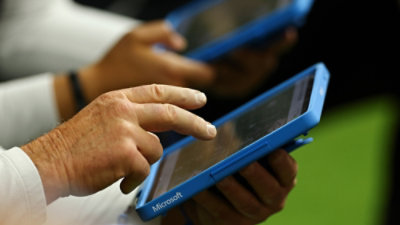 Close-up of multiple people using tablet devices, with hands interacting with touchscreen displays.