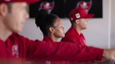 Three people in red uniforms seated side by side, focused on a computer-based activity.