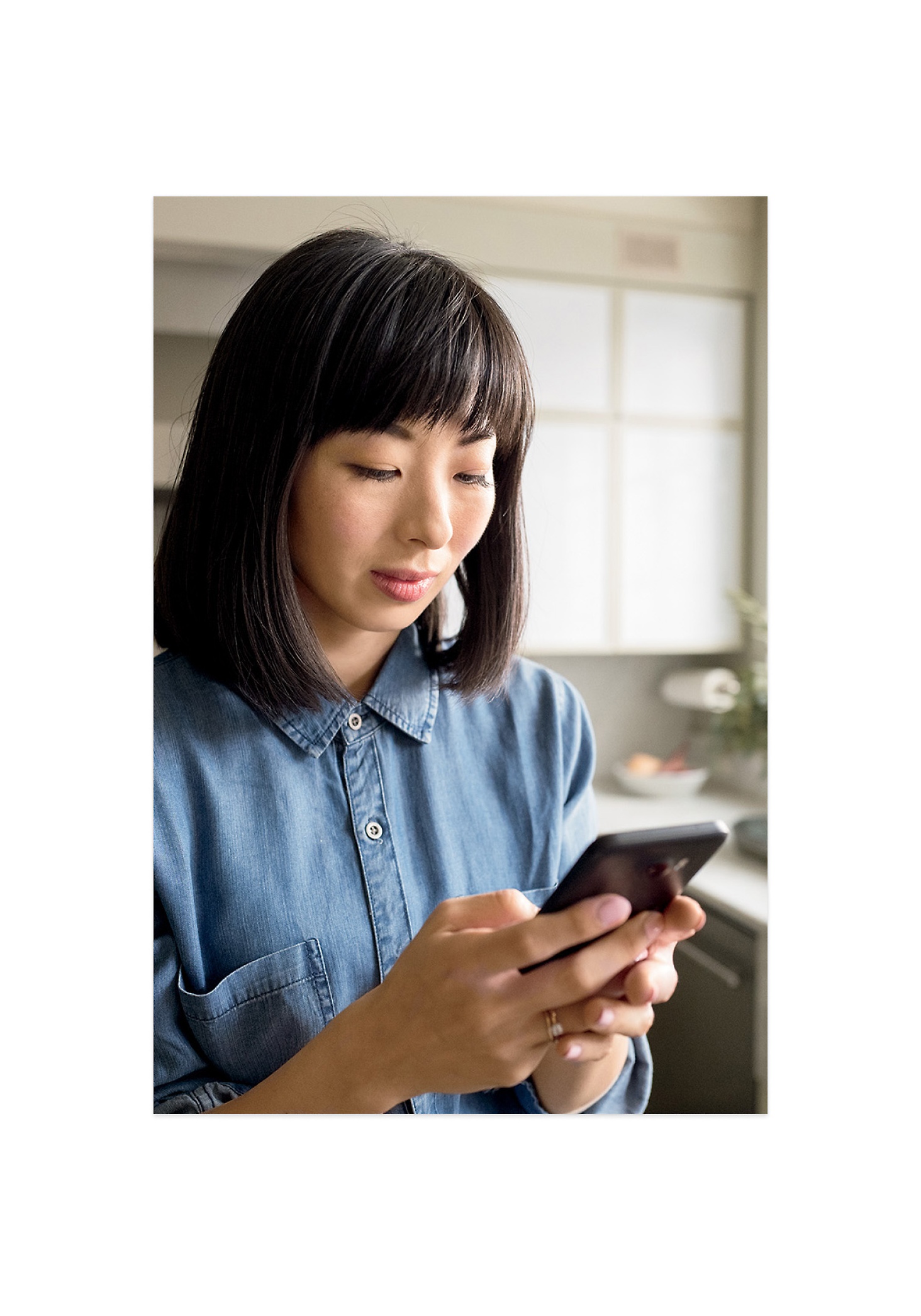 A woman wearing blue colored top checking her phone using both hands