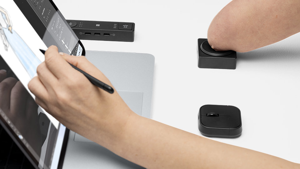 Человек с ограниченными физическими возможностями использует Microsoft Adaptive Hub и Button со своим устройством Surface.