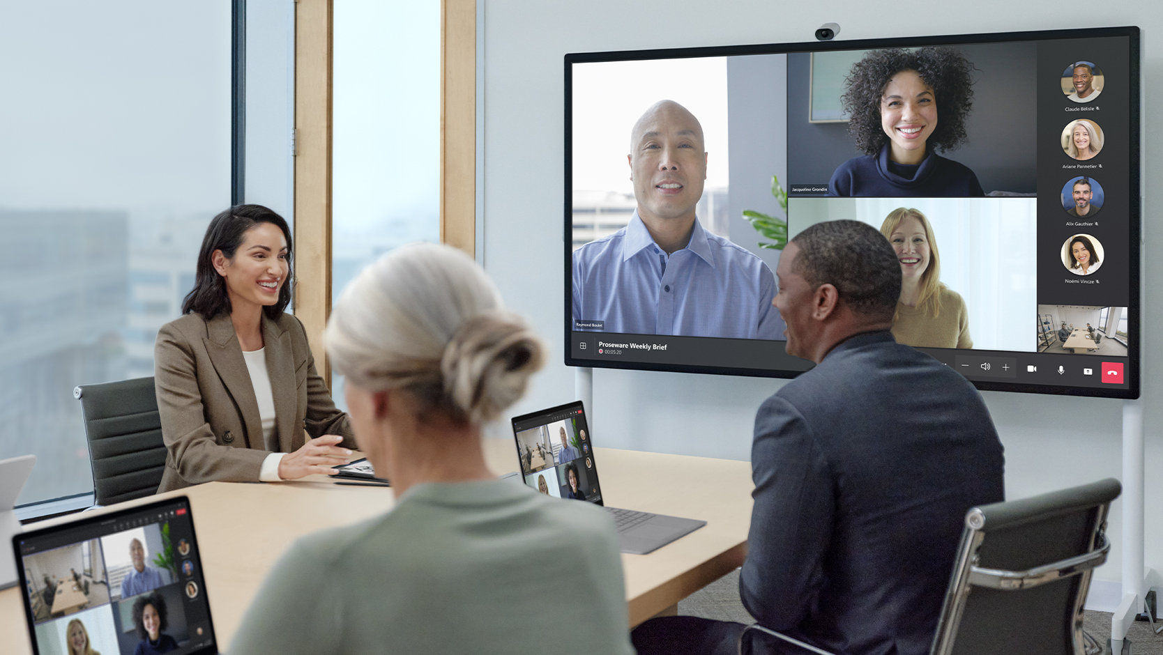 Teammitglieder, die sich sowohl im Büro als auch an anderen Standorten befinden, nehmen mit einem Surface Hub 3 for Business und einer Surface Hub Smart Camera an einer Besprechung in Microsoft Teams teil. 