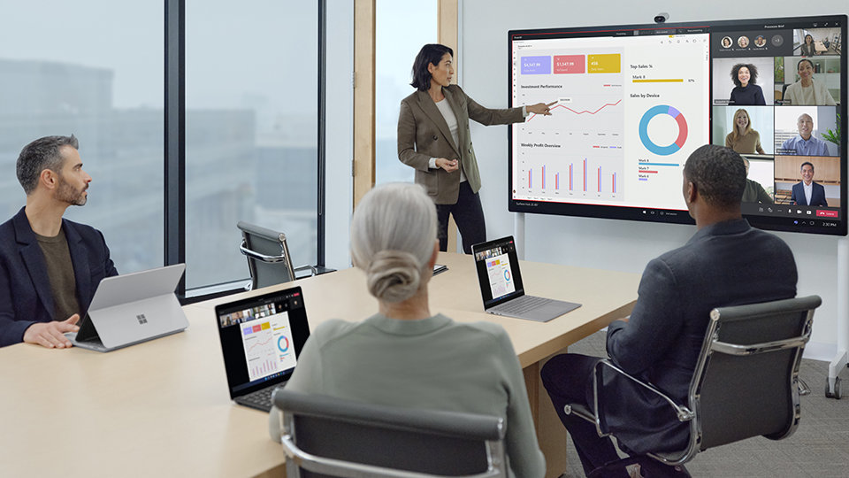 A person uses a Surface Hub 2 S and a Surface Hub 2 Smart Camera to present an infographic to team members who are in-office and remote..