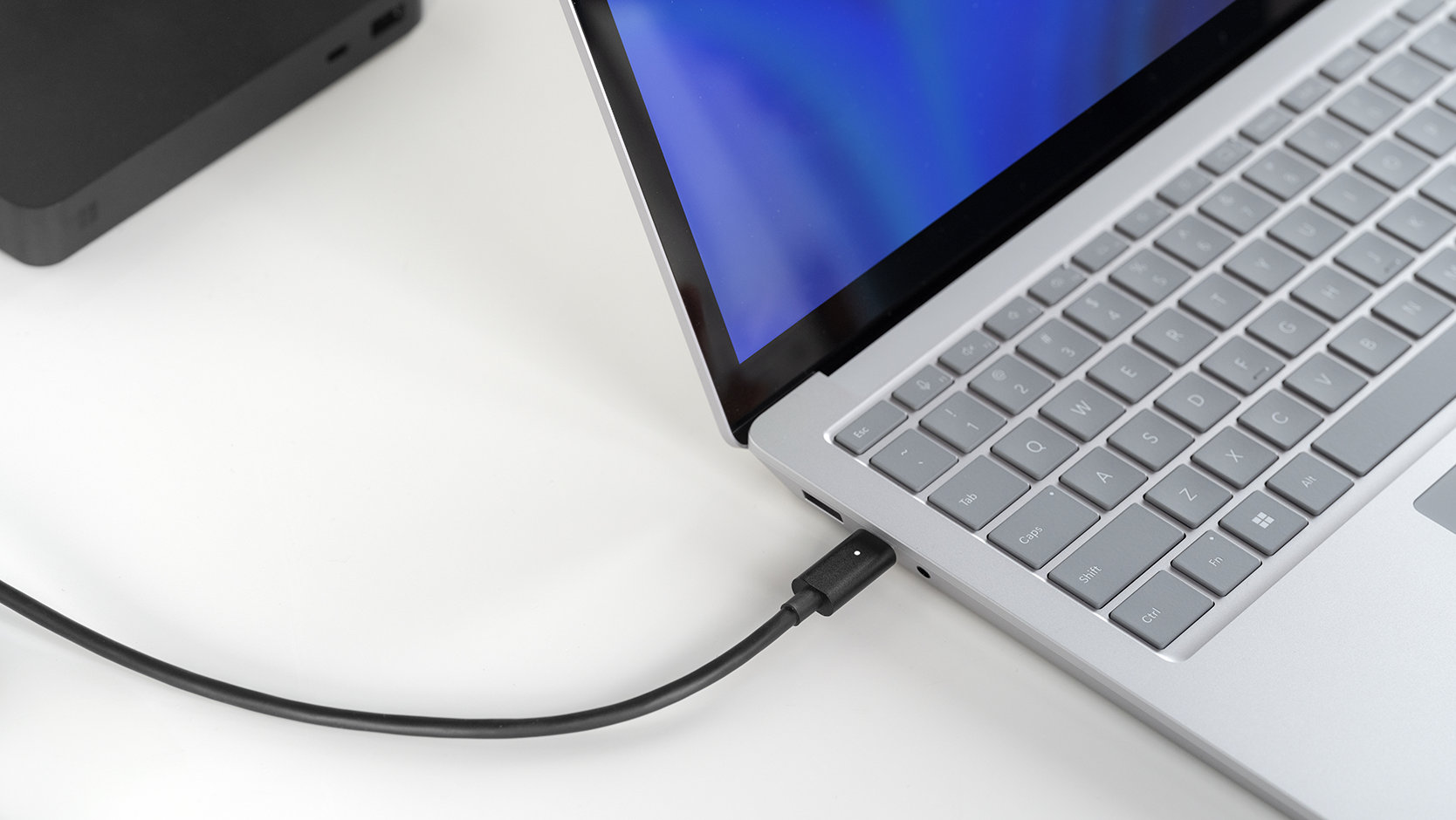 Un Adaptador Surface Thunderbolt™ 4 conectado a un dispositivo Surface Laptop 6 para empresas.
