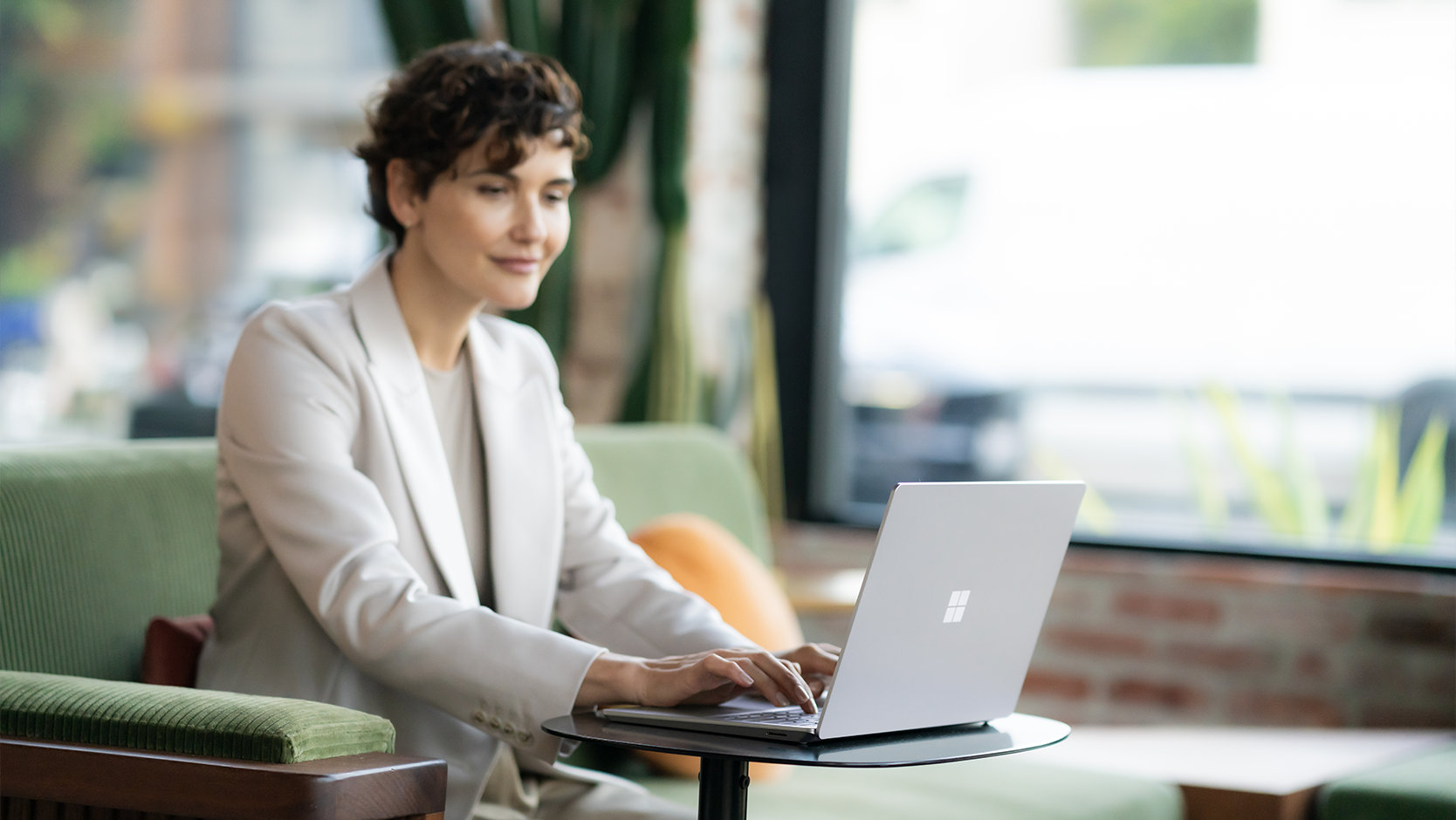 En person i en dress bruker Surface Laptop 6 for næringslivet på et offentlig sted, som foreslår sikkerheten til enheten.