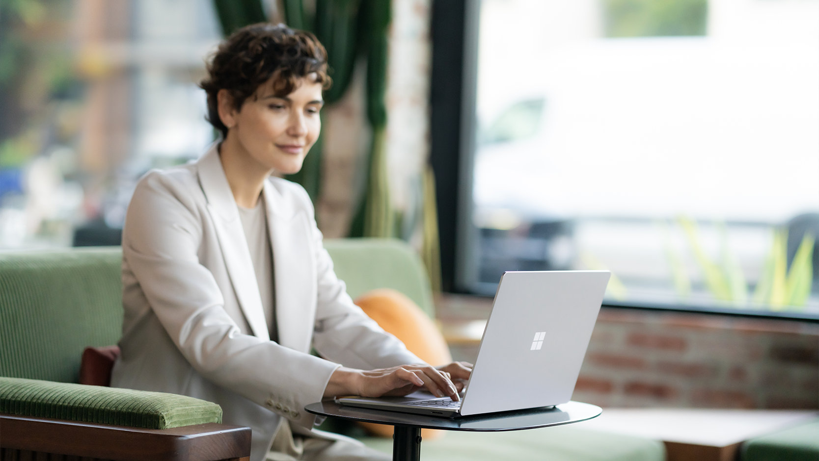 Une personne portant un habit utilise un Surface Laptop 6 pour l’entreprise dans un espace public, ce qui suggère la sécurité de l’appareil.