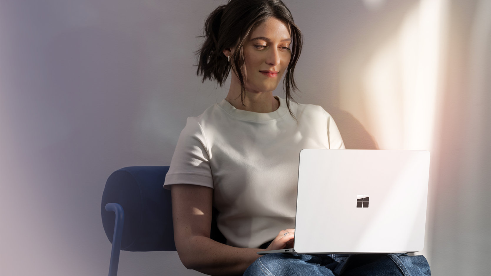 A person smiles using a Surface Laptop for Business device, suggesting the ease of signing in on the device. 
