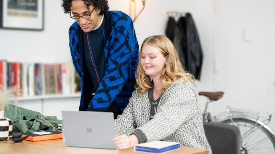 Una persona muestra la pantalla de su Surface Laptop Go 3 para empresas a otra persona, destacando que el núcleo protegido ha proporcionado la protección necesaria para bloquear sus datos confidencial.