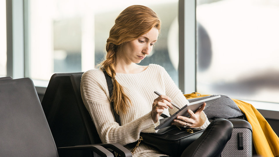 Eine Person wartet in einem Wartezimmer und verwendet einen Surface Pen.