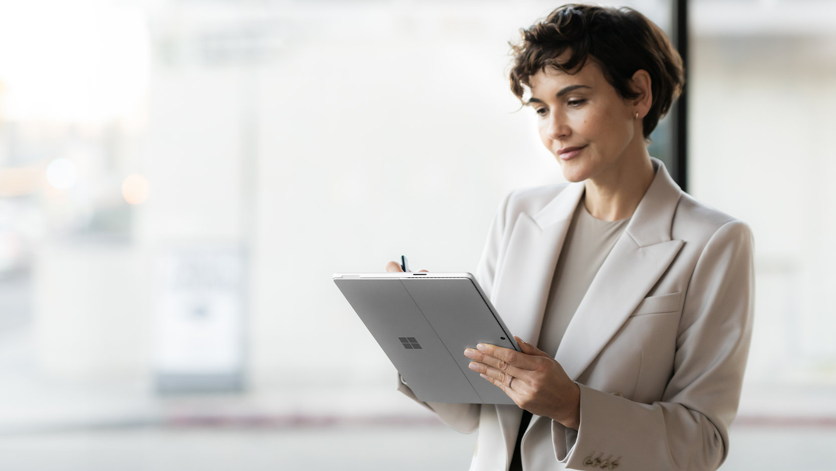 Una persona vestida de traje usa Surface Pro 10 para empresas en un espacio público, indicando la seguridad del dispositivo. 