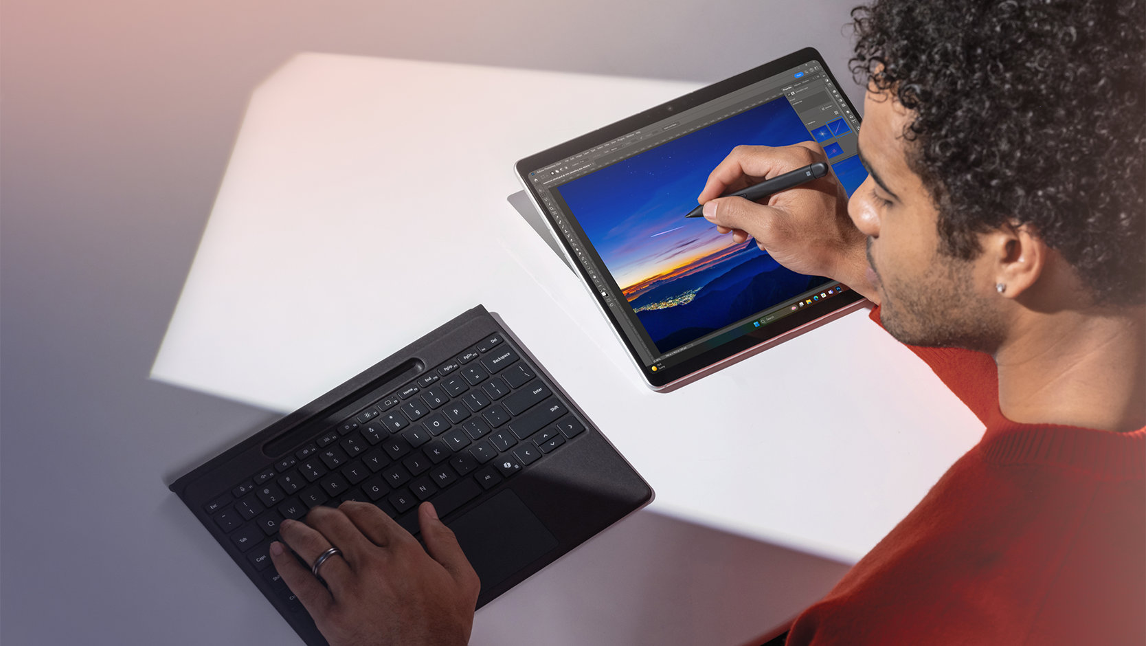 取り外した 法人向け Surface Pro フレックス キーボード（ペン格納トレイ付き）でタイピングしながら、法人向け Surface スリム ペン を使用して Surface デバイスの画面で描画する人。