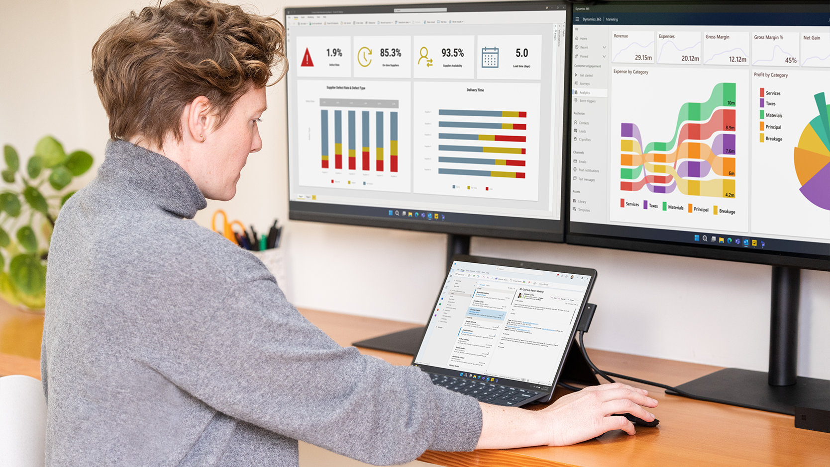 Een persoon gebruikt een Surface Pro-toetsenbord voor zakelijk gebruik aangesloten op een Surface-apparaat bij een bureaubladopstelling met monitors. 