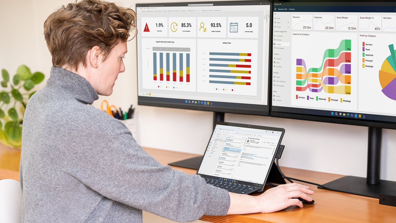 En person använder ett Surface Pro Keyboard för företag som är anslutet till en Surface-enhet som står på ett skrivbord tillsammans med bildskärmar.