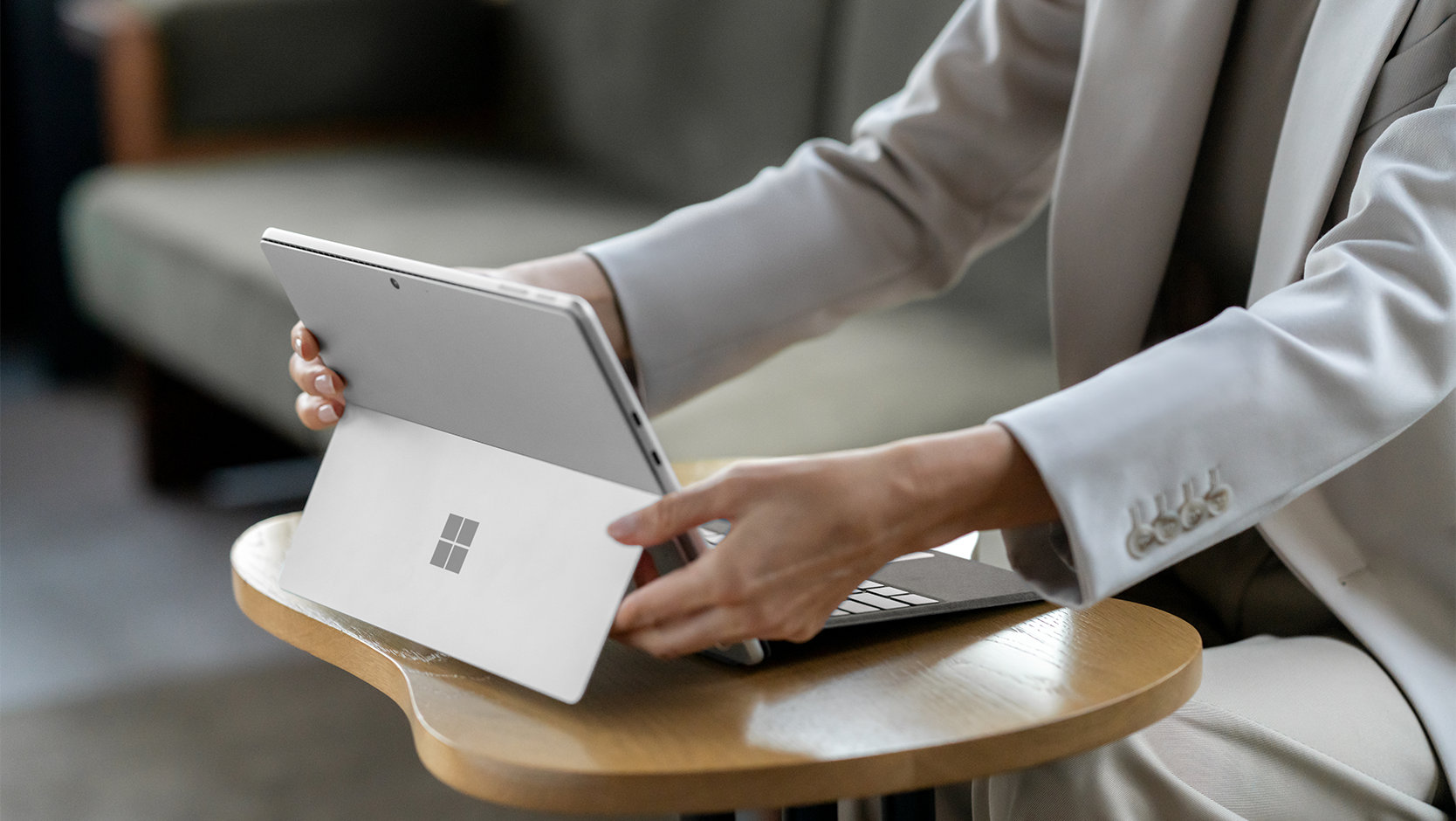 A person adjusts their Surface device while it is securely attached to a Surface Pro Keyboard with pen storage.