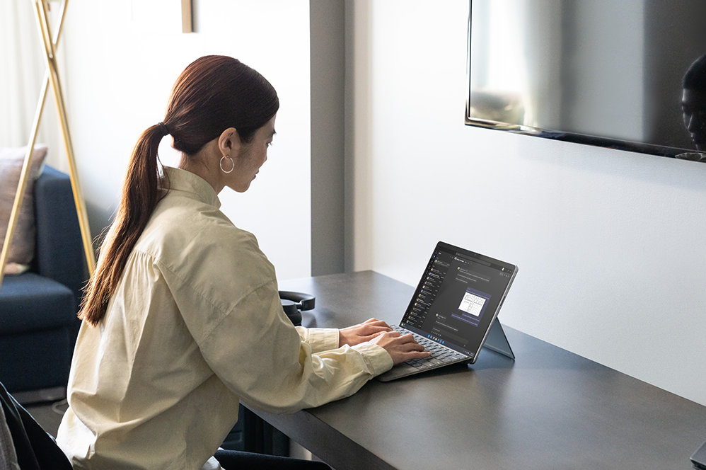 Uma pessoa sentada à secretária a utilizar um Teclado Signature para Surface Pro.