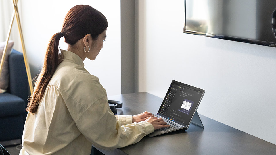 A person uses a Surface Pro Signature Keyboard while seated at a desk.