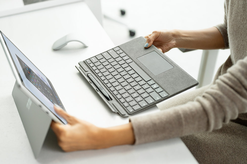 A person attaches a Surface Pro Signature Keyboard to a Surface Pro 9.
