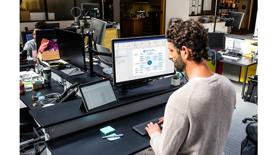 一个人使用平板电脑设备和一个大型桌面显示器来创建平面布置图。