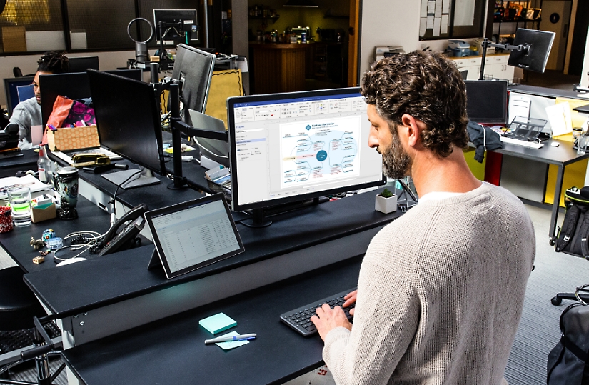 一个人使用平板电脑设备和一个大型桌面显示器来创建平面布置图。