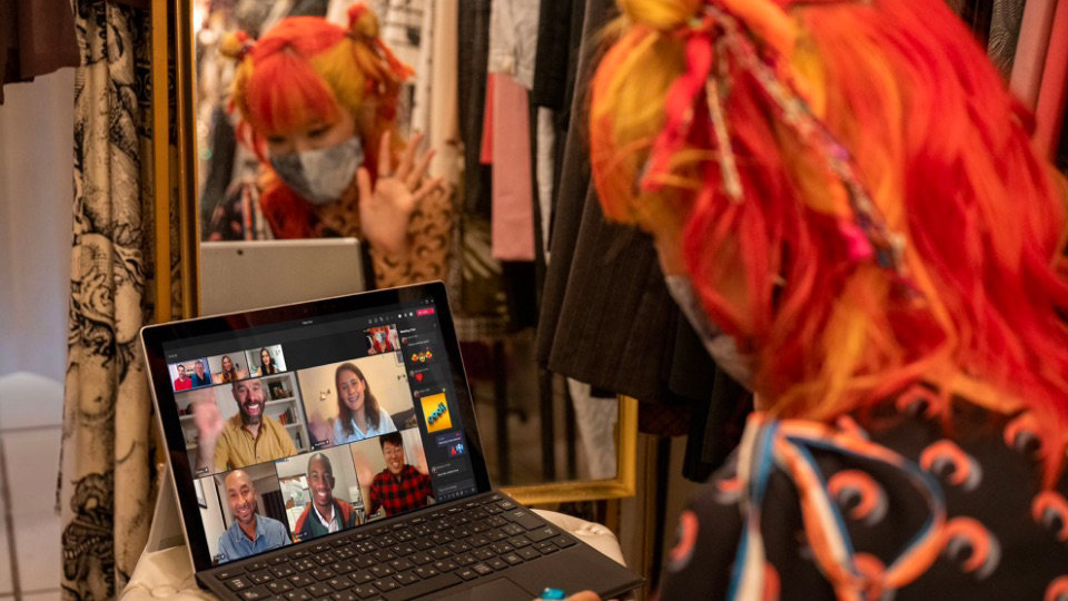 A worker at a vintage clothing store in Shibuya showing off the store on a Teams video call using a laptop. 