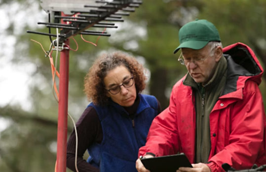 Two people reading a tablet connected to weather hardware