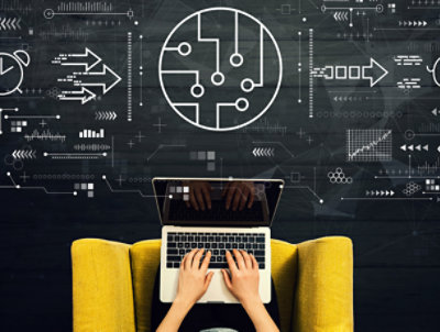 使用膝上型電腦的人的俯視圖，前面的牆上投影著與技術和創新相關的數位圖形。