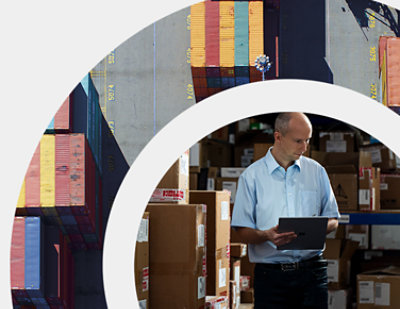 Een man in een magazijn die naar een tablet kijkt.