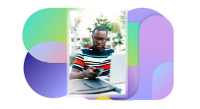A person sitting at a table outdoors using a laptop and mobile phone.