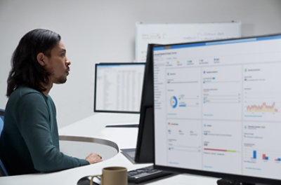 A person working at a desk with multiple screens displaying data and Azure