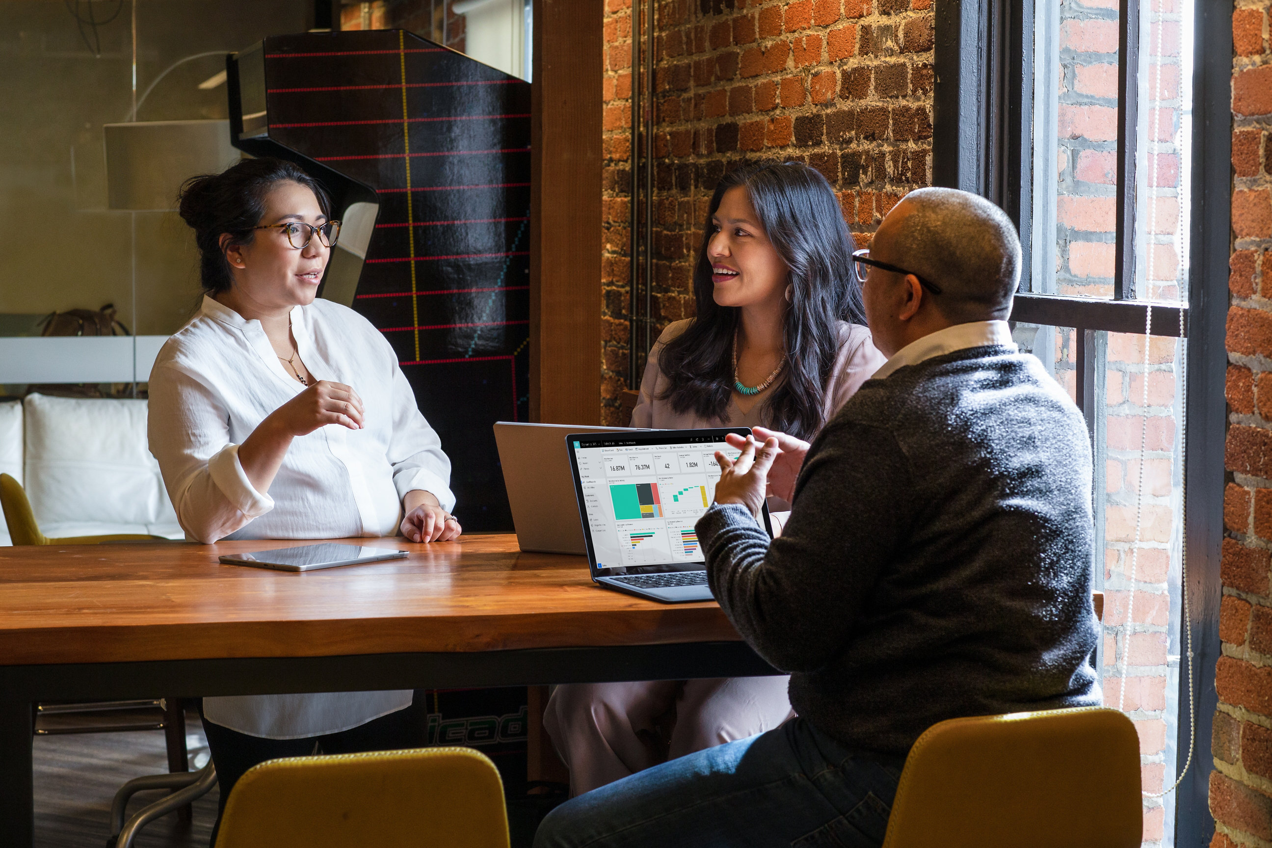Three business colleagues have a discussion while sitting at a table.