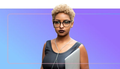 An adult wearing glasses and holding a laptop.