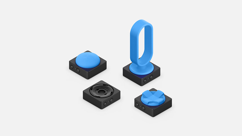 Botões Adaptáveis da Microsoft com partes superiores de botão impressas em 3D em várias formas e tamanhos.