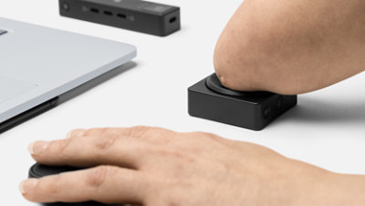 Une personne souffrant d’un handicap physique appuie sur un bouton adaptatif Microsoft.