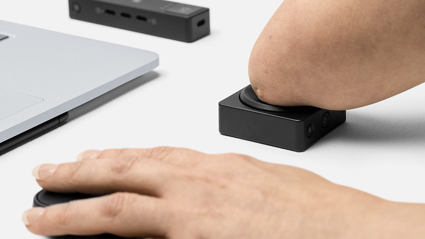 Una persona con discapacidad física pulsa un botón adaptable de Microsoft.
