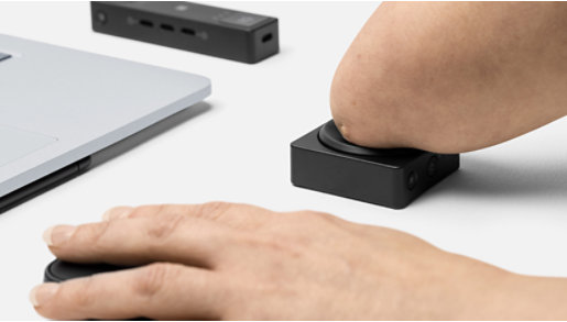 A person who has a physical disability uses Microsoft Adaptive Hub, Mouse, and Button with their laptop.