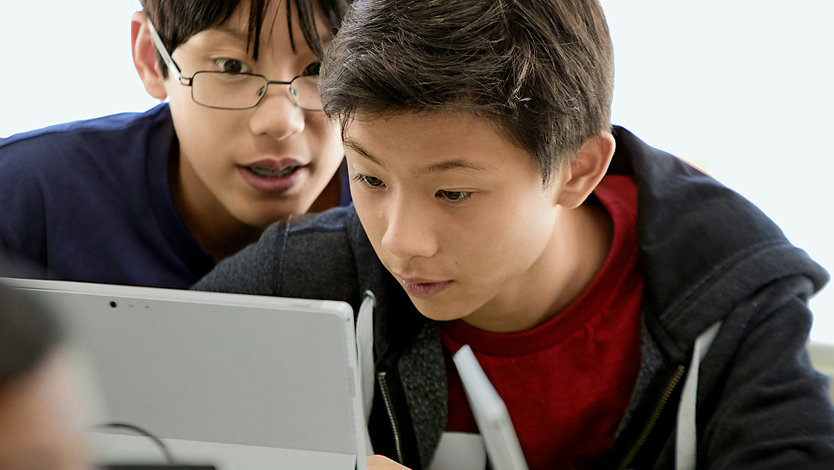 Two children reading something on a Surface device.
