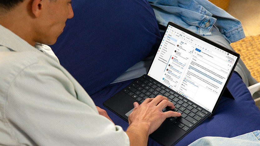 Egy fiatal férfi a Microsoft Outlookban beérkező személyes üzeneteit ellenőrzi egy Surface Pro eszközön.