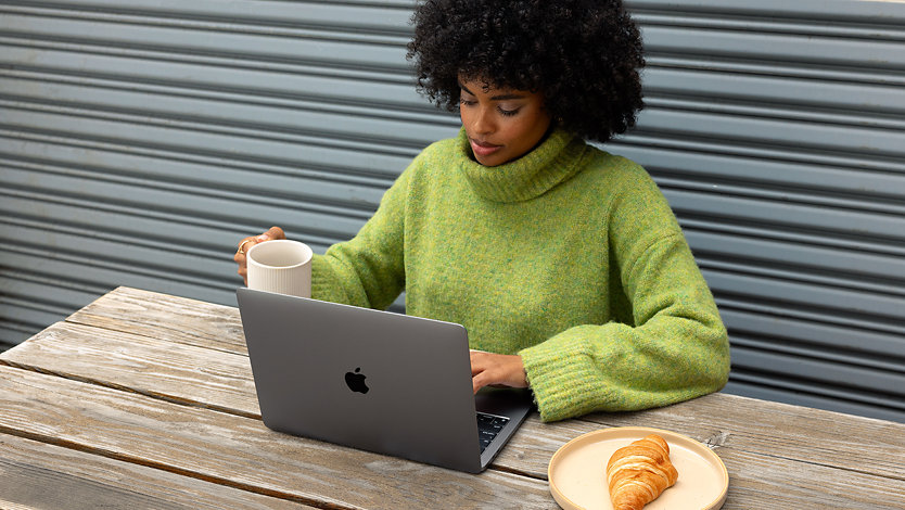 Women using Microsoft 365 on MacBook while seated at an outdoor cafe