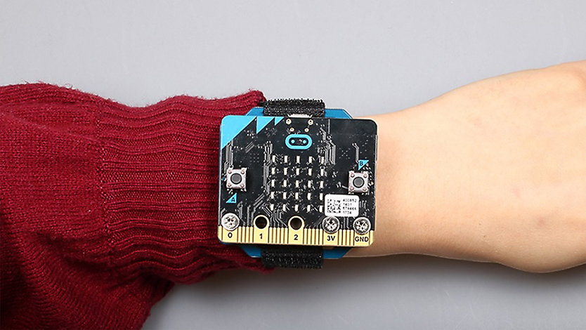 ベルト付きバングルで人の手首に装着された Micro:bit。