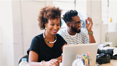 Two photographers sit together and collaborate using a computer.