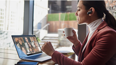 Žena pijucka šolju čaja i razgovara sa svojim saradnicima putem servisa Microsoft Teams.