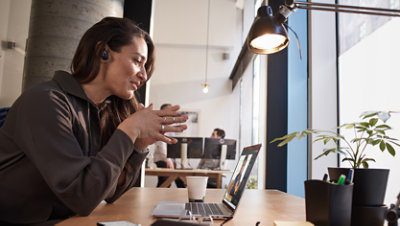 Une femme assise à une table et prenant un appel vidéo. 