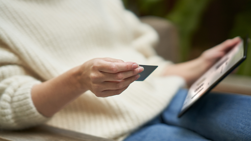 Person holding a credit card and a tablet.