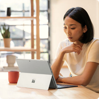 A person sitting at a table, working on a Surface Pro for Business, which is attached to a Surface Pro 13-inch Flex Keyboard for Business. 