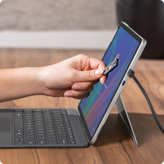 Uma pessoa aproxima um cartão NFC do ecrã de um Surface Pro para Empresas para iniciar sessão de forma rápida e segura.